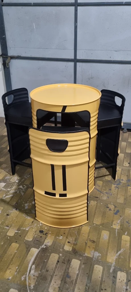 Mustard-yellow steel-barrel table with black drum chairs tucked underneath